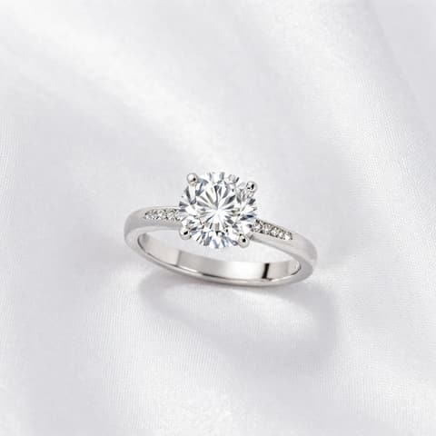 Jewelry: silver solitaire diamond ring on white silk