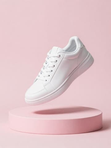 White leather sneaker floating above a pink round podium