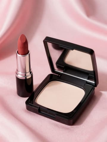 Nude-rose lipstick and black-cased pressed powder on pink silk